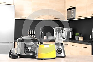 Modern domestic appliances on wooden table in kitchen.