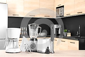 Modern domestic appliances on wooden table in kitchen