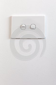 Modern double light switch on white wall.