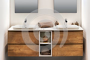 Modern double washbasins on wooden cupboard in illuminated light