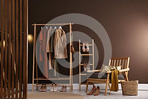 Modern dressing room interior with clothing rack and comfortable armchair