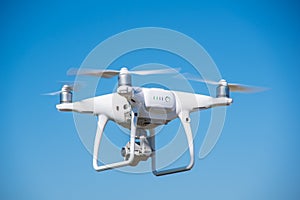 The modern drone, quadrocopter is in the air against the background of the sky and grass