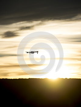 Modern drone silhouetted against sunset