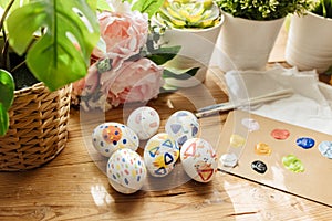 modern easter eggs painted. Brushes and paints with flowers and plants. Happy easter concept on a wooden background