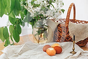 Modern Easter eggs  on rustic table with spring flowers, candle,  basket. Stylish red and yellow Easter eggs painted in natural