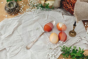 Modern Easter eggs  on rustic table with spring flowers, candle,  basket. Stylish red and yellow Easter eggs painted in natural