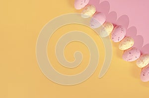 Modern Easter Holiday Composition with Small Eggs on a Pink-Yellow Geometric Background.