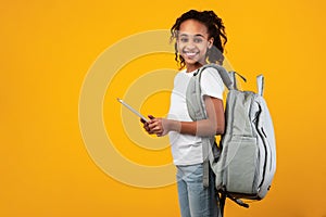Black girl wearing backpack standing with tablet at studio photo