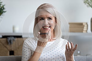 Modern elderly woman talk on cell using loudspeaker