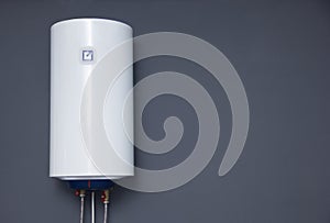 Modern electric boiler on a gray plain wall. White water heater. Space for text