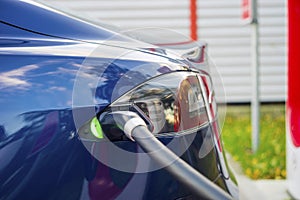 Modern electric car plugged to charging station in a parking lot