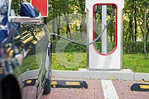 Modern electric car plugged to charging station in a parking lot