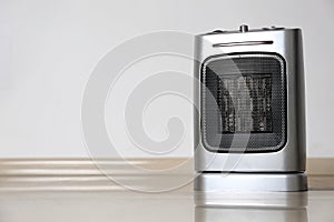 Modern electric fan heater on floor in room, space for text