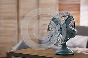 Modern electric fan on wooden table indoors. Space for text