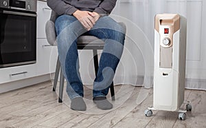 Modern electric heater in the kitchen against the background of a sitting man in a chair. Heater concept with automatic