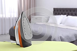 Modern electric iron on board in bedroom. Laundry day