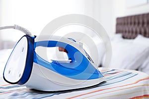 Modern electric iron on board indoors. Household appliance