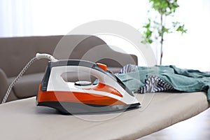 Modern electric iron and clothes on board indoors