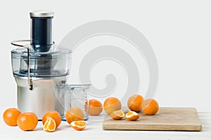 Modern electric juicer and fresh oranges, white background