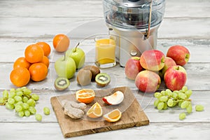 Modern electric juicer, various fruit and glass of freshly made juice, healthy lifestyle