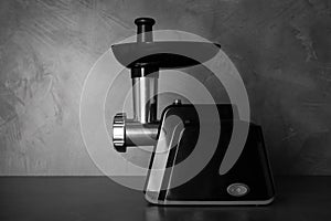 Modern electric meat grinder on black table. Space for text