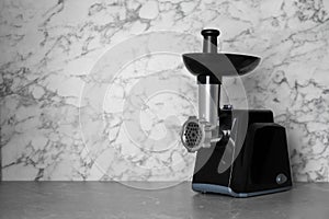 Modern electric meat grinder on grey table. Space for text