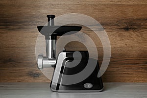 Modern electric meat grinder on light wooden table