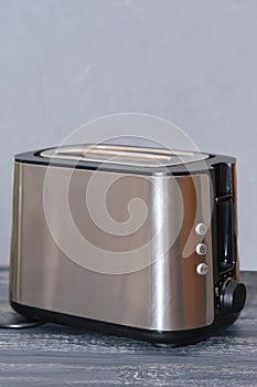 modern electric metallictoaster on grey wooden table in kitchen. electrical appliances for cooking, vertical