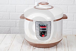 Modern Electric Multi Cooker on a white wooden table in kitchen. Copy space