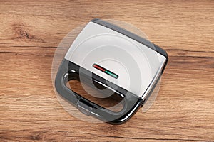 Modern electric sandwich maker on wooden table, above view