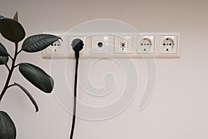 Modern Electrical Outlet. Electrical outlet, cable and electrical plug on a white wall background. Wall white electrical plugs