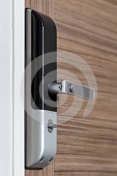 Modern electronic door lock with handle on wooden door