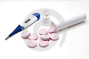 Modern electronic thermometer with pills closeup on white background
