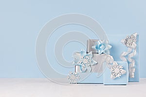 Modern elegant gift boxes wrapping in pastel blue color and silver metallic with ribbons and bows on white and blue background.