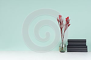 Modern elegant home workplace with black books, glass vase with red branch in green mint menthe interior on white wood table. photo