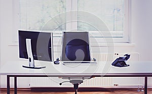 Modern empty office space desk with computer, phone and chair.