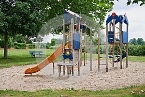 Modern empty playground beside green trees