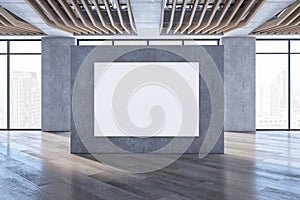 Modern empty spacious concrete interior with blank white mock up poster on wall, wooden flooring, windows, city view and daylight