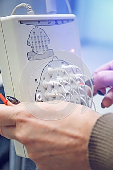 Modern encephalograph and doctor hands with wires in clinic. EEG or Electroencephalography research