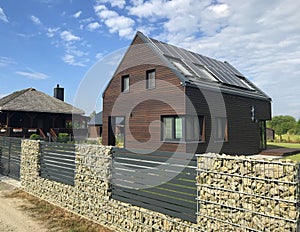 Modern energy efficient house with solar panels and gabion fence