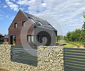 Modern energy efficient house with solar panels and gabion fence