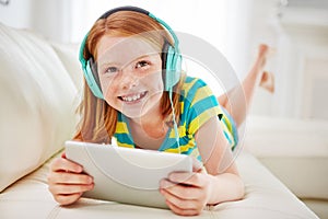 Modern entertainment for modern kids. a little girl using a digital tablet with headphones at home.