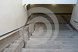 Modern entrance to the pedestrian tunnel, descending down empty. Stairway down to the underground new passage. Beige