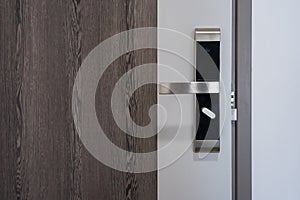 Modern entrance wooden door with metal doorknob handle and security electronic digital door keycard lock systems