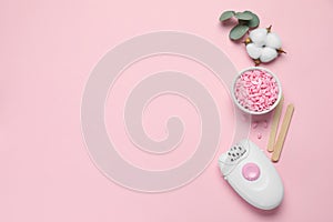 Modern epilator, depilatory wax and fluffy cotton flower on pink background, flat lay. Space for text