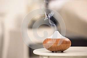 Modern essential oil diffuser on table indoors