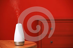 Modern essential oil diffuser on table indoors