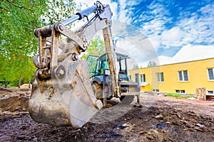 The modern excavator performs excavation work on the construction site. Front view of a digger bucket of digging ground