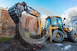 The modern excavator performs excavation work on the construction site. Front view of a digger bucket of digging ground