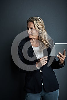 This modern exec only uses modern tools. Studio shot of a mature businesswoman using a digital tablet against a grey